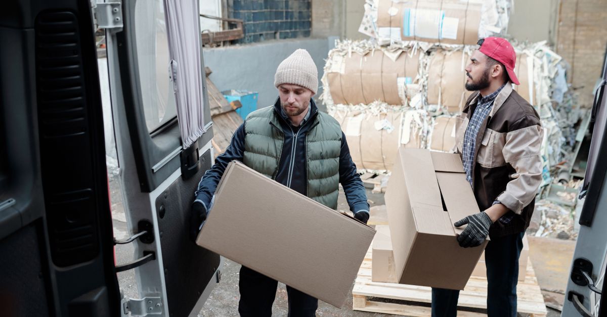 Operarios trasladan cajas de cartón junto a balas compactadas